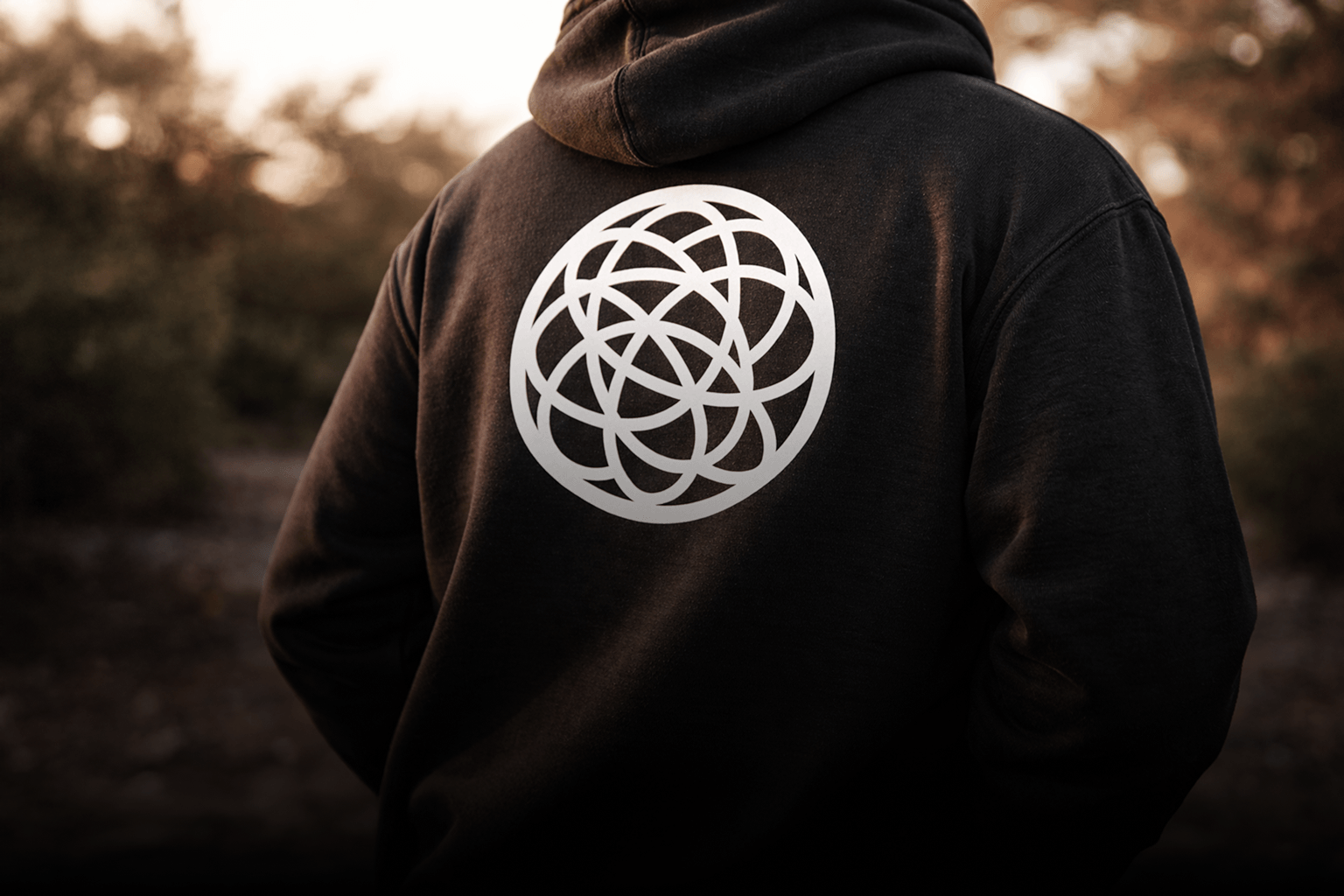 Person wearing a minimal SHAMBLES logo hoodie black with a white geometric symbol on the back
